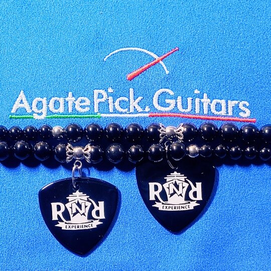 Due ciondoli di pietra di agata nera con incisione su sfondo azzurro e logo di agatepick.guitars 