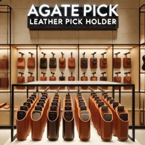 immagine di negozio di strumenti musicali con insegna a sfondo nero e scritta di colore bianco agatepick leather pick holder sullo sfondo sulla parete si vedono molti portaplettri in pelle in esposizione, in primo piano della fotografia molti portaplettri in pelle allineati uno dietro l'altro
